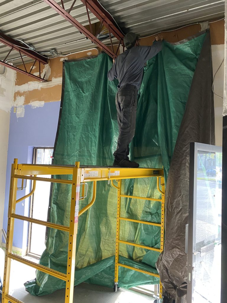 Worker protects windows prior welding reinforcements for HVAC units. JW Portable Welding & Repairs 2021