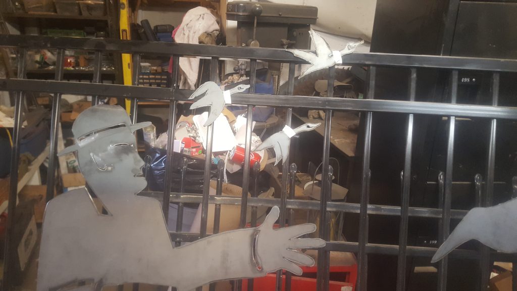 Decorative wrought iron fence with 4 geese, 2 cattail plants, 1 man statue and large sign. JW Portable Welding & Repairs 2019, London Ontario