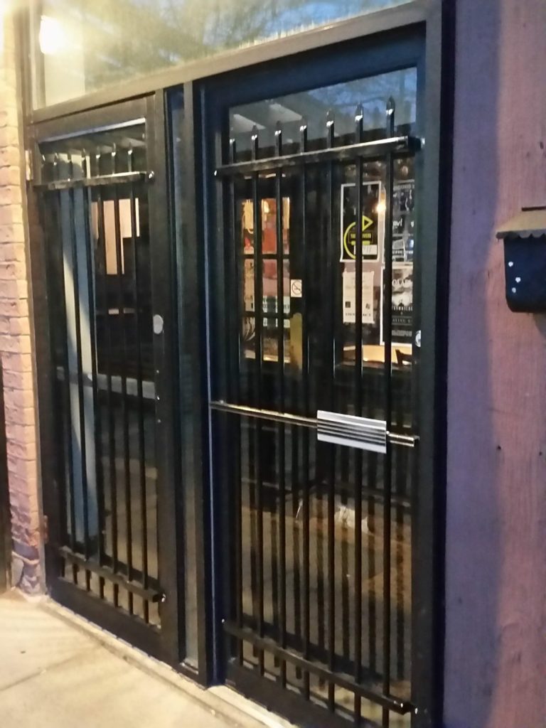 Door security grills without the sign installed on bar's door with glass panel. JW Portable Welding & Repairs 2019, London, Ontario