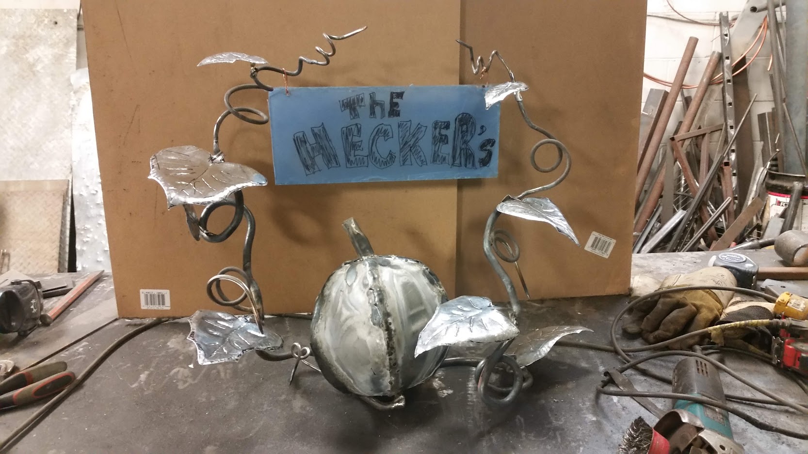 The metal pumpkin plant with multiple leaves and large pumpkin has a family name temporarily fitted to two branches. JW Portable Welding & Repairs, 2020 London, Ontario