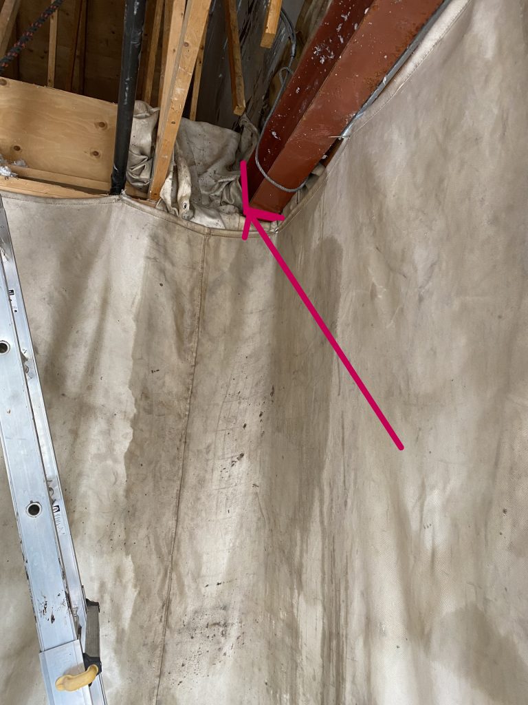 The red arrow points where the cut has to be made. Sprayed with water fire blankets mitigate the elevated fire hazard. Notice a large fire blanket protecting the 2x4s in the room and multiple fire blankets surrounding the place we have to cut. JW Portable Welding, London, Ontario, 2022