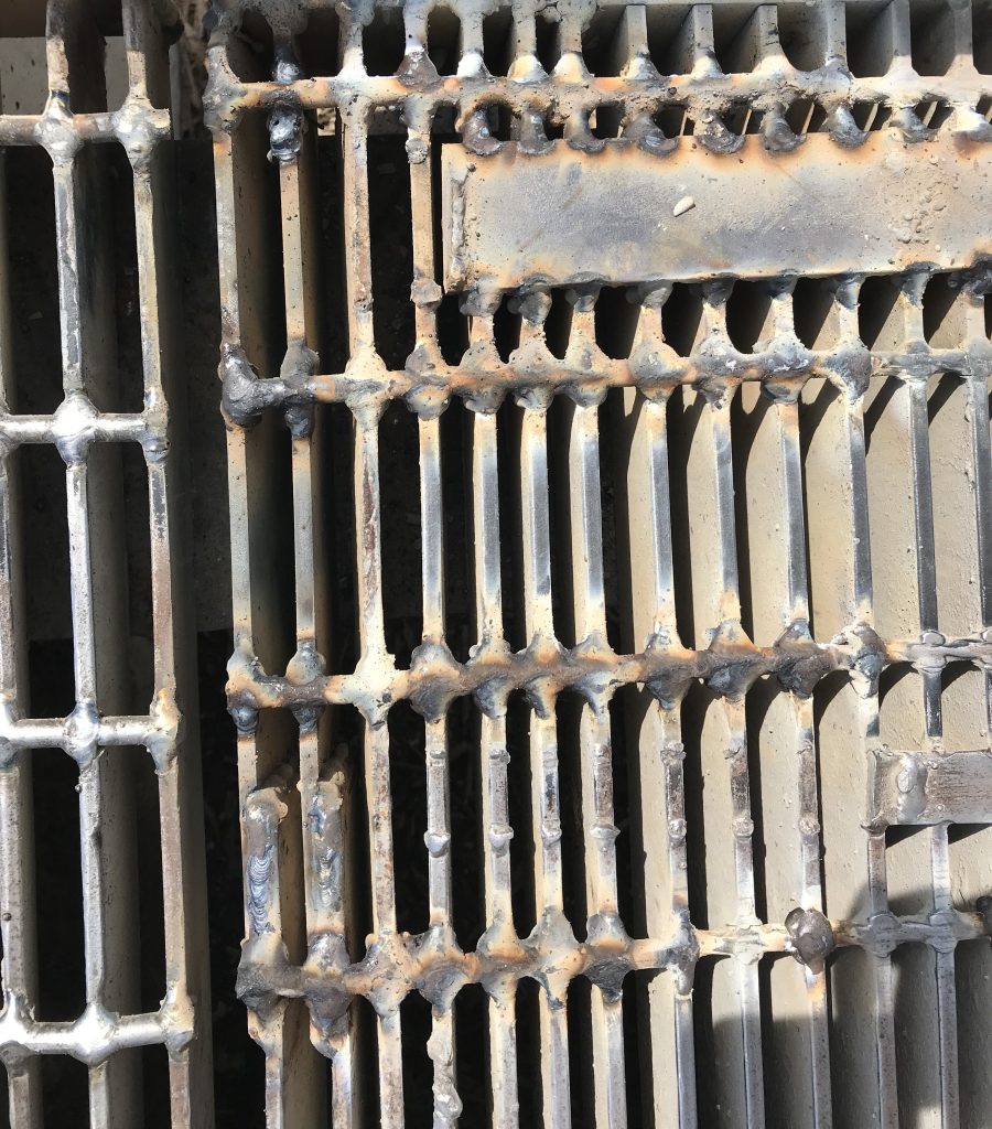 Welded rods and a flat bar to multiple blades of grating to increase its structural integrity. JW Portable Welding, London, Ontario, 2021