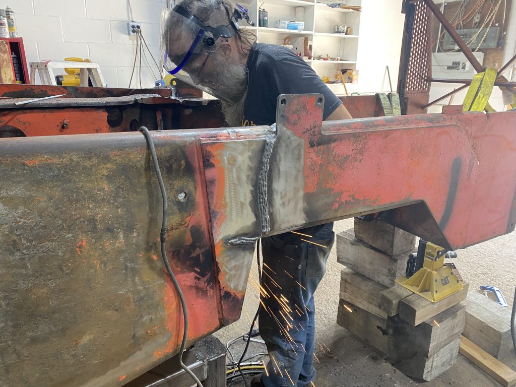 The cracks 1 and 2 has been welded in the outside plate on the right hand side of the skidder. The cap of these repair welds has not been grinded off flash yet. The worker standing between frames is grinding something. August 11, 2025 for JW Portable Welding & Repairs, Lucan Ontario