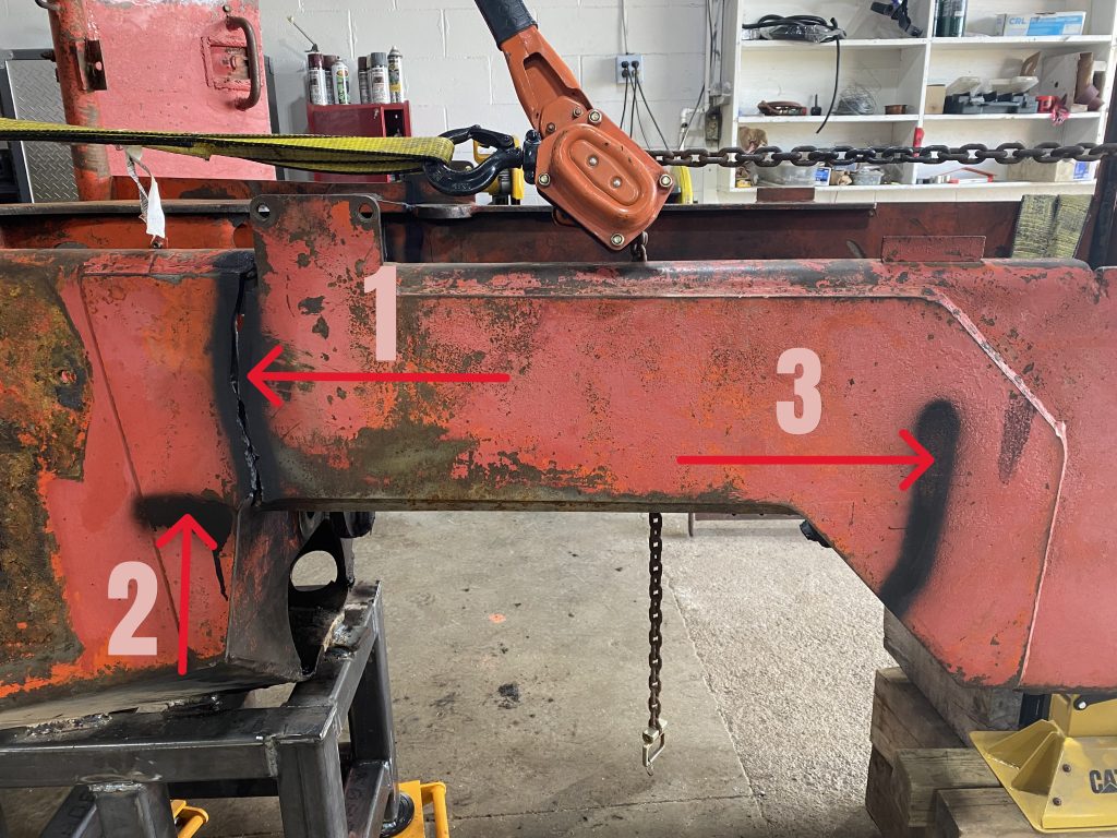 Cracks 1, 2 and 3 as they are visible on the skidder's right hand side in the outside plate. Each crack is marked with a black paint and numbered. The red arrow points to corresponding crack. Crack 1 provides a complete separation of outside plate and causes complete structural separation of frame's front. The attached manual lever chain hoist and hydraulic jack keep the front frame's position. August 11, 2025 for JW Portable Welding & Repairs, Lucan Ontario