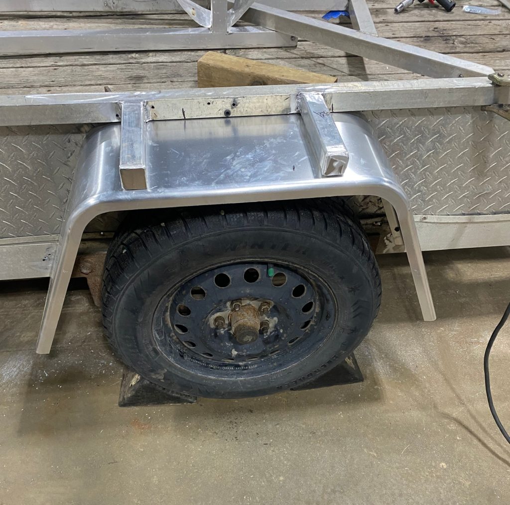 The new fender is installed on old utility trailer. The 2 aluminum  square tubing are welded horizontally to the wall frame for easier mounting and for protection of the fender.. These square tubings protect the aluminum fender from the heavy load on placed on the top of the fender.  JW Portable Welding & Repairs. June 18, 2025 Lucan Ontario.