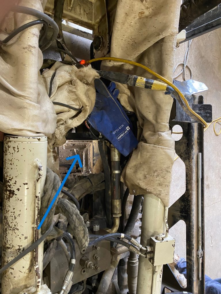 The highly congested space for heavy equipment repair by welding of crack and a fish angle stabilizing the joint. The zoom out points the benefits of SMAW welding. The blue arrow points to welded area. JW Portable Welding, London, Ontario, May 2, 2023