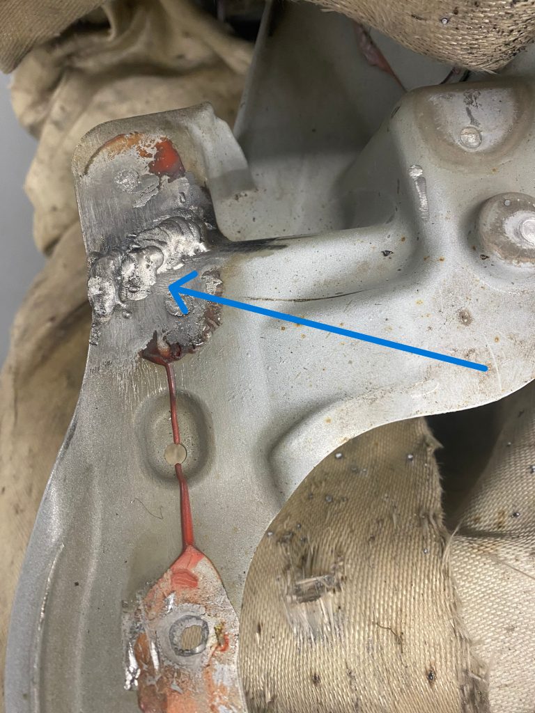 Third repair weld on aluminum bracket of Tesla car. The blue arrow points to a wide aluminum corrective weld. December 6, 2023 JW Portable Welding & Repairs , Aylmer, Ontario.