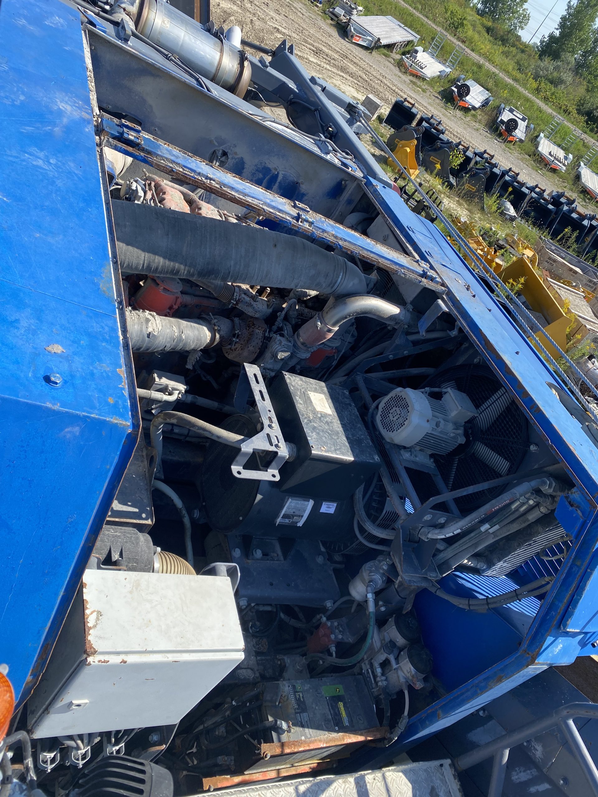 Both damaged covers of the rock crasher's engine are removed. The engine compartment containing the engine and its components is clearly visible The blue color side walls have grooves for cover engagement. The huge size of this machine allows to put in perspective sizes of the covers.