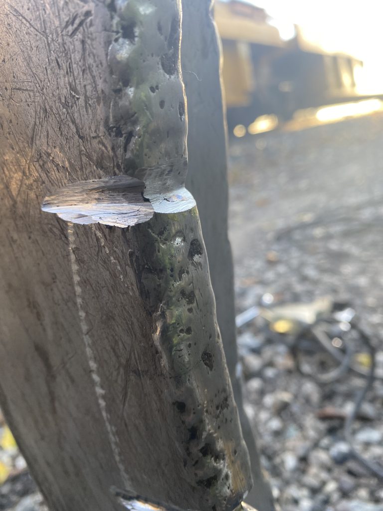 Grooved crack in arm of grapple railway crane in the lawyer of impact and surface friction resisting layer and structural steel. Look at color difference. London ON, 2024 for JW Portable Welding & Repairs.