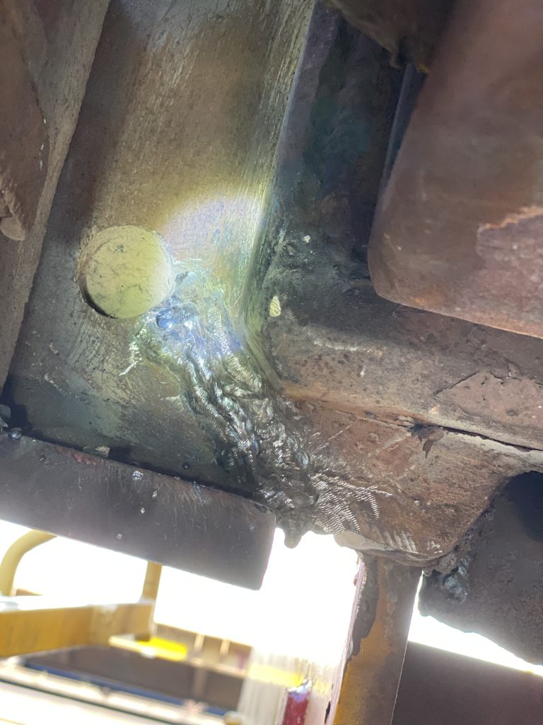 The crack has been welded with multi-pass weld in extremely difficult condition while laying down on the railway tracks. The weld is on a running away from the welder surface. We knew that this is just a temporary solution since the stress between the edge of the bumper and the bore will crack again. London ON, 2024, JW Portable Welding & Repairs.