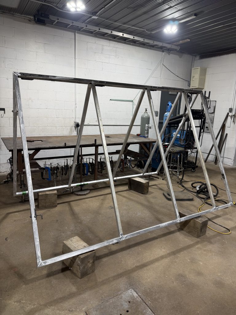 Aluminum fabrication of a huge multi-sectional aluminum structure for the portable sign. The structure consists of 2 sections 8 feet by 10 feet joined by hinges. For JW Portable Welding, 2026, Shop in Lucan,, Ontario