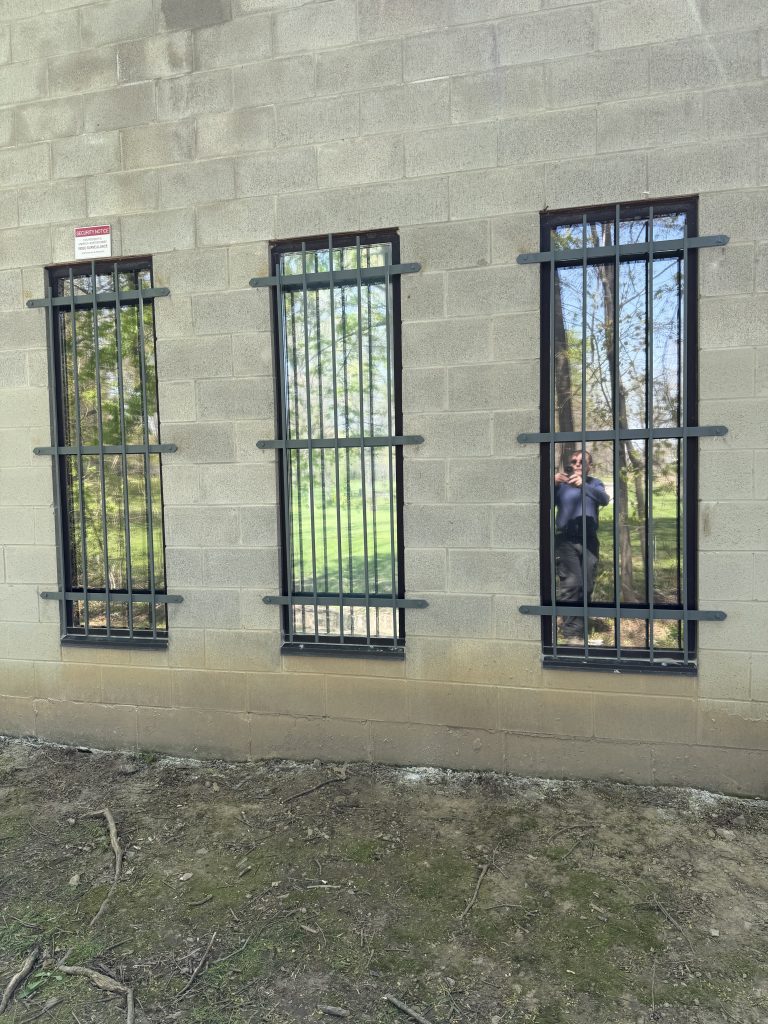 Exterior window grill in local synagogue painted grey for more pleasing effect. The design's goal is to impose strength and medieval steel look. Metal fabrication by JW Portable Welding & Repairs, 2026, London.
