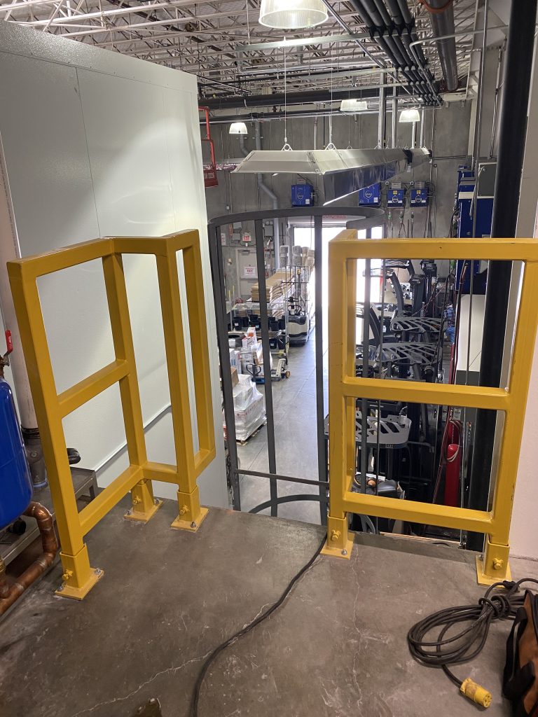 New safety barrier on the factory floor that accommodates to entrance of the ladder. Painted yellow. Installed, designed and fabricated by JW Portable Welding & Repairs, 2023, London