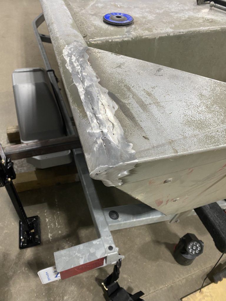 Welded rim transition between deck and hull near transom on the fishing aluminum boat. The polished aluminum reflects the light from the well done repair. The client requested smooth polishing for better weld inspection. For JW Portable Welding & Repairs, 2024, Lucan
